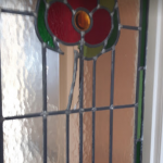 close up of stained glass window with red flower
